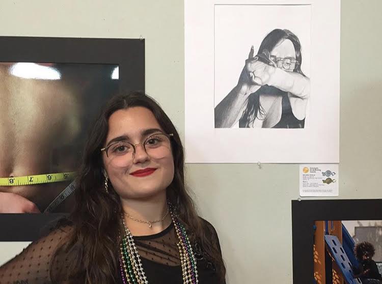 Melanie Cilella posing next to her art at the Scholastic Art and Writing Awards in West Palm Beach, Fla. where she won two gold keys, two silver keys and three honorable mentions in the category of drawing and illustration. 
