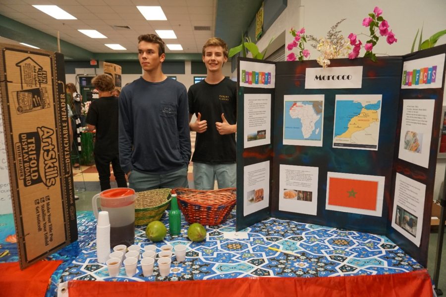 Sophomore Robert Miller and sophomore Dainius Horan standing at their project booth at Mardi Gras.