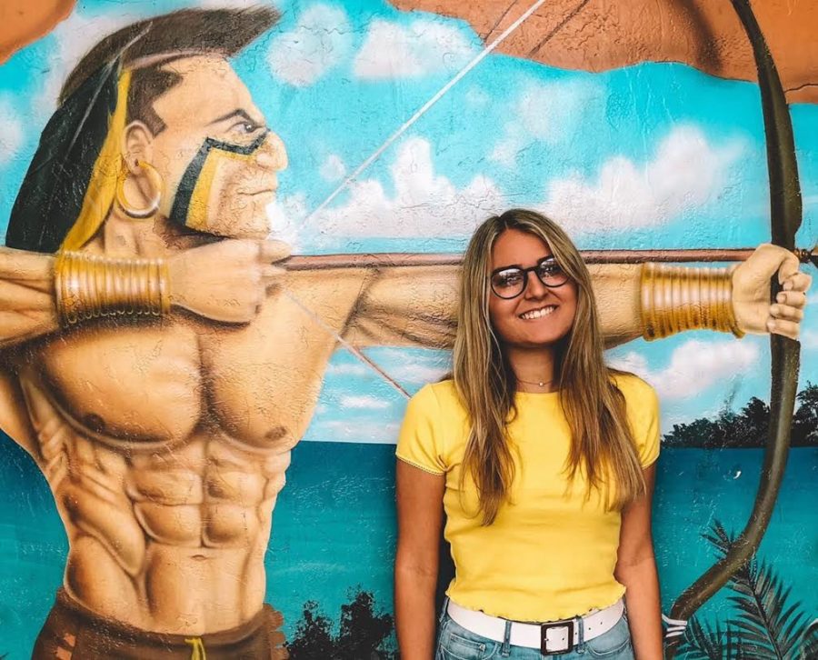 Senior class president Lily Tardonia stands in front of the Warrior mural in the atrium, a senior hangout spot. 
