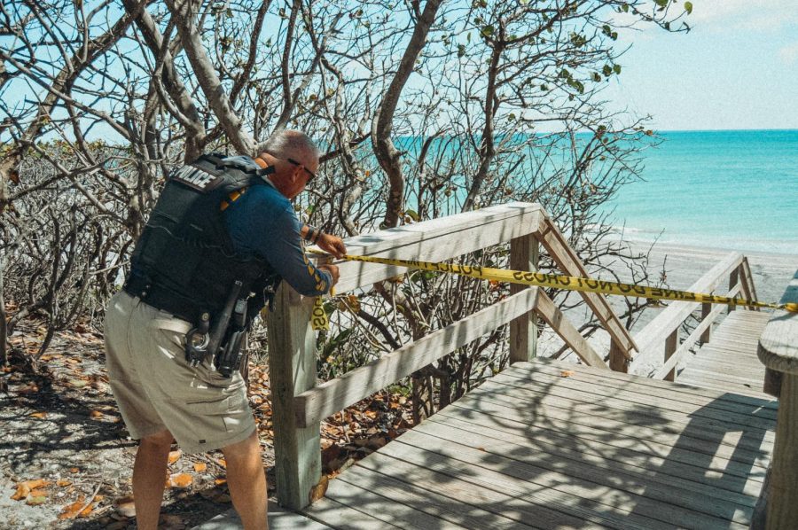 Jupiter police officer tapes off  one of many walkways to Jupiter Beach that is closed due to coronavirus (1 April)