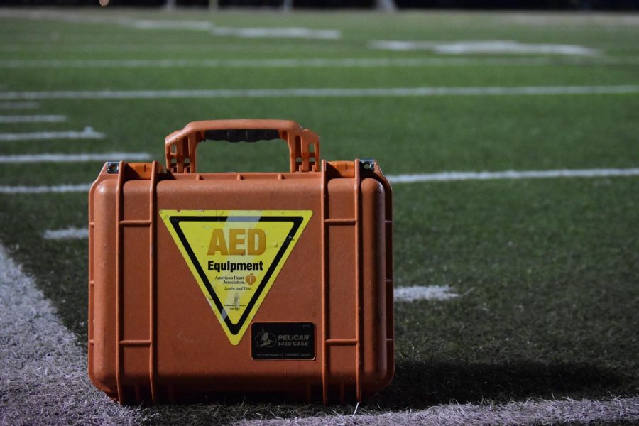 An Automated External Defibrillator rests on the sideline.