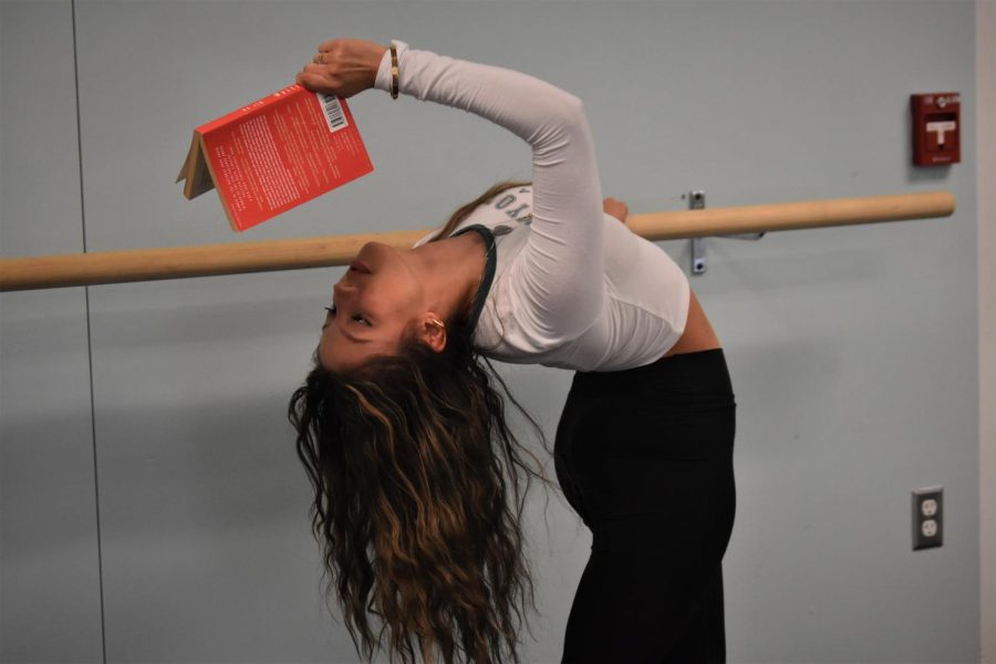 Dancer Angela Pfirman reads her book while doing a unique dance pose.