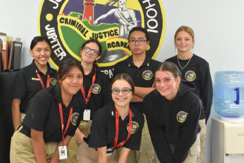 Criminal Justice Academy students pose in their classroom below their emblem.