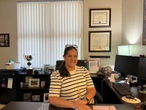 New Principal: Ms. Saunders in her office with awards and degrees displayed in the back.