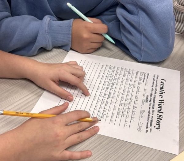 Elementary school student working on writing activity with Junior Journalists volunteer