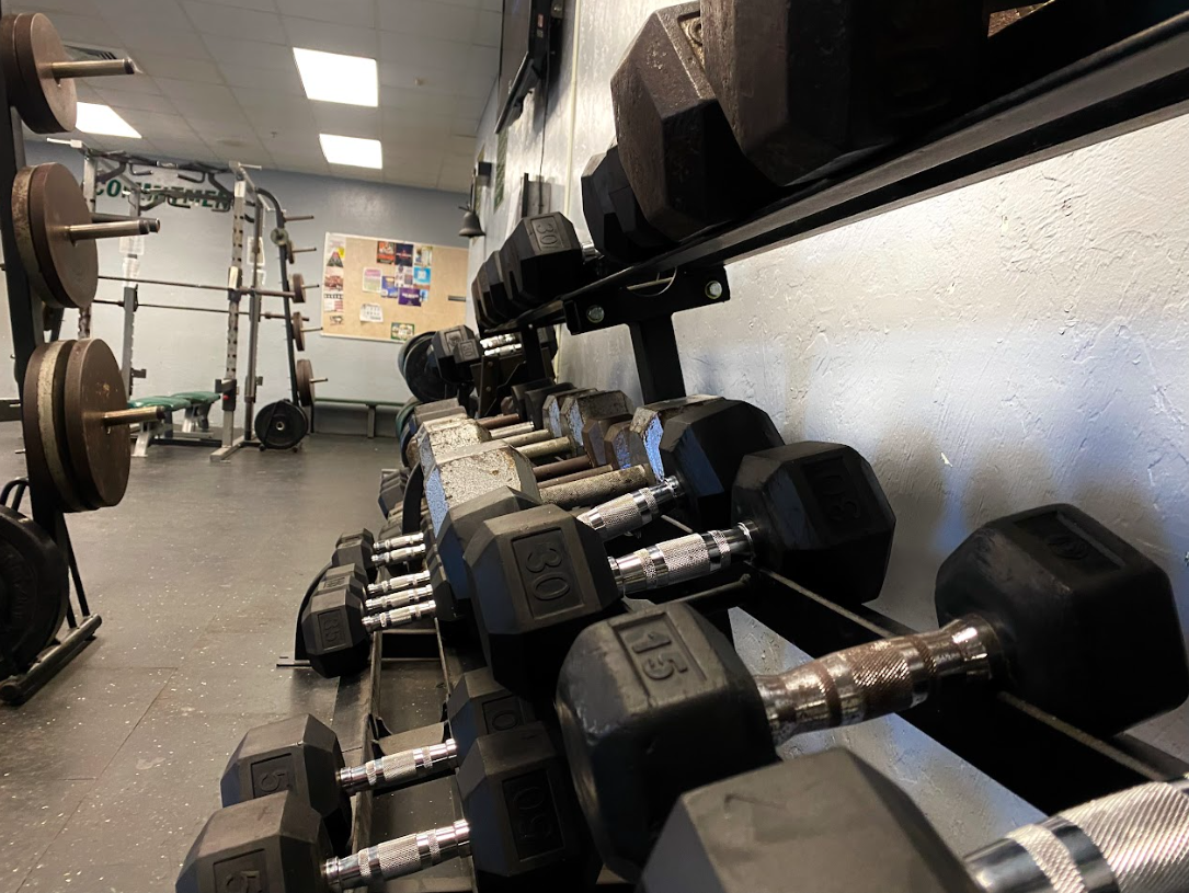 Weights organized in Jupiter High schools' weightlifting room on the right and machines used by the athletes on the left.